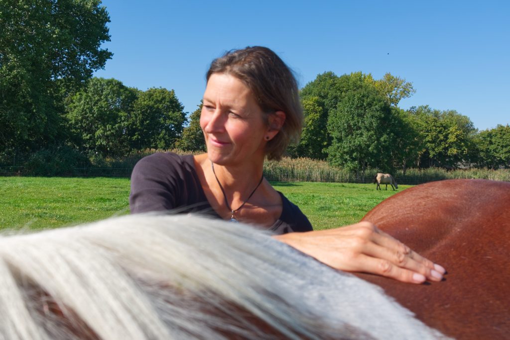 Pferdeosteopathin Tatjana Schmitt und ein Pferd bei der Traumatherapie